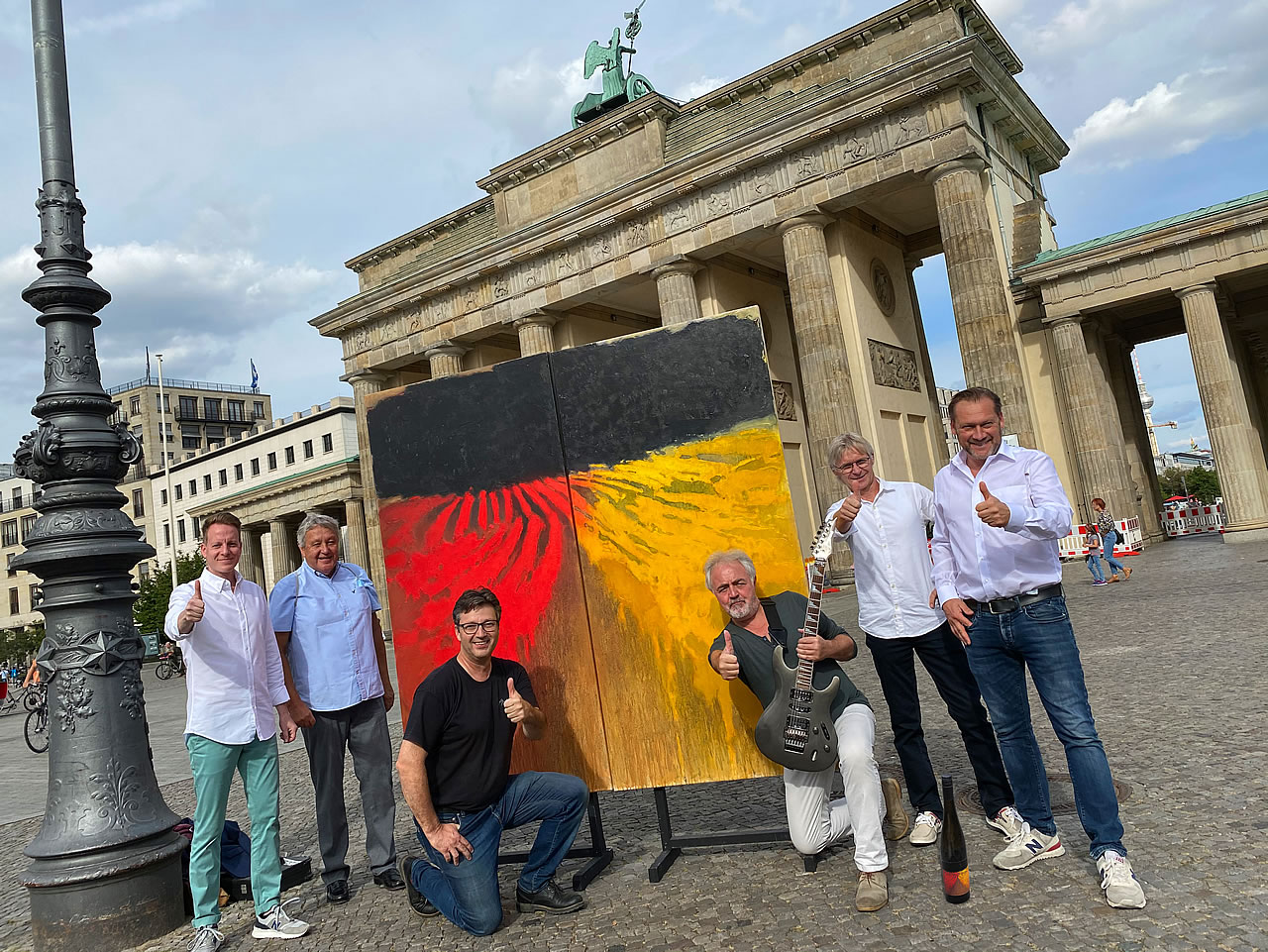 Team EINHEIT mit Originalgemälde und Flasche vor dem Brandenburger Tor